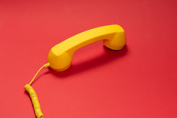 Yellow handset on red background.