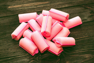 Soft foam comfortable hair curlers on wooden background.