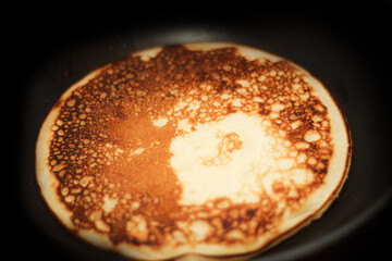 Pancake is fried in a pan. Rosy hot sweet breakfast.