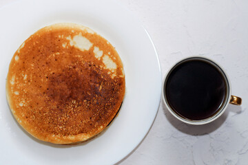 Pancakes in a white plate with black coffee. Rosy hot sweet breakfast.