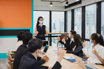 Multiethnic business group wearing face mask and showing thumbs up congratulated with female executive about company cooperation agreement during the meeting