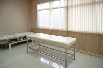 Empty patient auscultation bed with sunlight shining on curtain at hospital