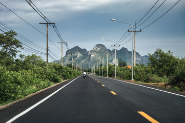 View of green mountain range with utility pole and lamppost on highway in countryside at Sam Roi Yot