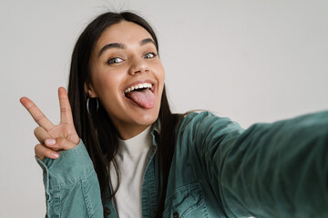 Young woman gesturing peace sign while taking selfie photo