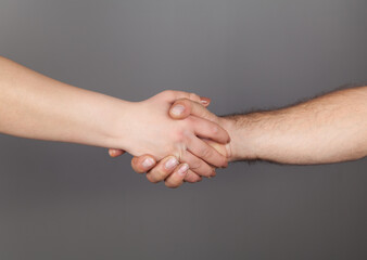 Hands of man and woman holding together, Gray background.