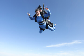 Fototapeta na wymiar Skydiving. Tandem jump. A barefoot girl is flying in the sky.