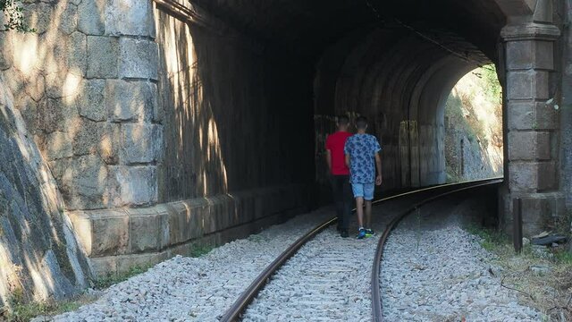 Pareja de chicos gay caminando por las v&iacute;as del tren en actitud cari&ntilde;osa y al final abraz&aacute;ndose