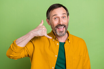 Photo of cheerful mature happy positive man make call me sign smile isolated on green color...