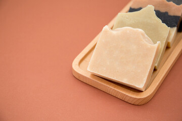 Assorted natural soaps on wooden tray isolated on brown
