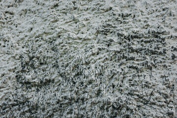 Background of an old wall made of pebbles and cement mortar covered with white lime.