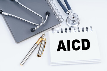 On the table are a stethoscope, a pen and a notebook with the inscription - AICD