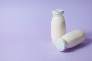 Bottles with probiotics and prebiotics dairy drink on light purple background. Bio yogurt with useful microorganisms. Production with biologically active additives. Fermentation and diet healthy food.