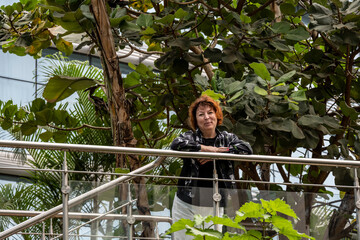 woman on a green balcony against a background of greenery 