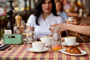 Young woman with friends drinking a coffee in a cafe terrace and white wine