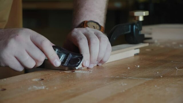 A carpenter works with a small jack-plane