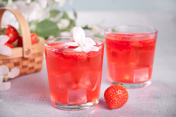 Strawberry cold refreshment lemonade with ice cube. White apple blossoms on the background. Spring concept.