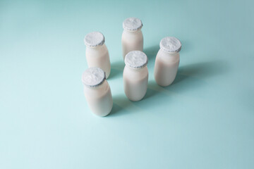Bottles with probiotics and prebiotics dairy drink on light blue background. Bio yogurt with useful microorganisms. Production with biologically active additives. Fermentation and diet healthy food.
