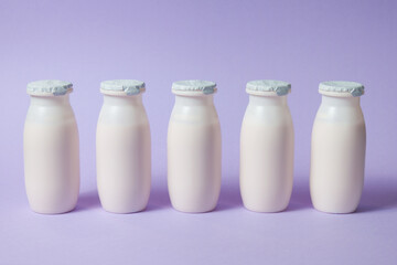 Bottles with probiotics and prebiotics dairy drink on light purple background. Bio yogurt with useful microorganisms. Production with biologically active additives. Fermentation and diet healthy food.