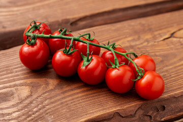 Cherry tomatoes on a wooden background. Fresh tomato branch. Vegetarian food.