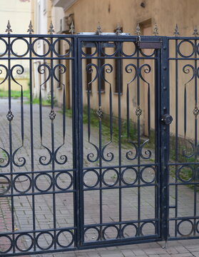 Black openwork wrought-iron fence with a closed gate