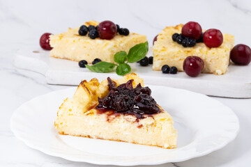 A piece of cottage cheese casserole with cherry jam. Piece of cheesecake with berries