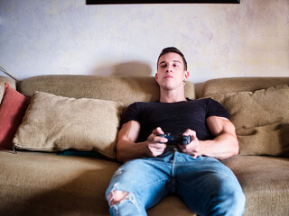 Attractive guy playing videogames with joystick in hand