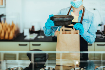 Saleswoman with protective face mask packs ice cream for her customer.
