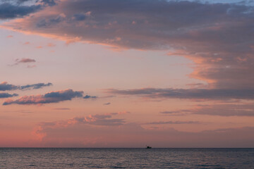 Dramatic evening sky with illuminated clouds and lonely fishing boat, sea image