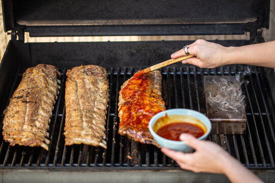 BBQ ribs being basted on the grill