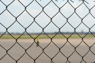 Naklejka premium Airport employees are on the runway. The territory of the private airfield is fenced with barbed wire and a fence. The traffic controller directs the plane.