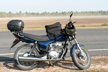 A motorcycle trip through the countryside in the summer. A blue motorcycle on a background of blue sky and white clouds.