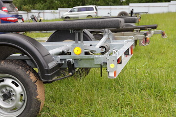 Boat trailers on outdoor grassy parking at summer day, motor boats storage and transportation - obrazy, fototapety, plakaty