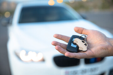 man holding car key with car