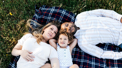 Content multiracial family lying on plaid on meadow