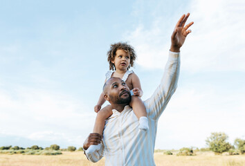Delighted black father and daughter having fun in summer field
