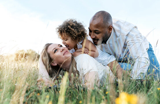 Delighted multiethnic family having fun together in field