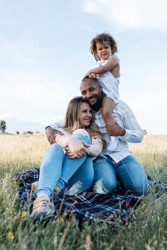 Delighted multiethnic family having fun together in field
