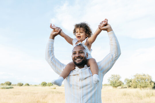 Delighted black father and daughter having fun in summer field