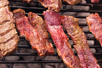 Raw beef meat is grilled, close-up. Beef steaks on a grill grid.