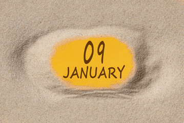 January 9. 9th day of the month, calendar date. Hole in sand. Yellow background is visible through hole. Winter month, day of the year concept