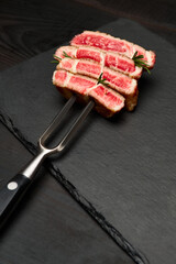 Studio shot of slices of steak on a meat fork