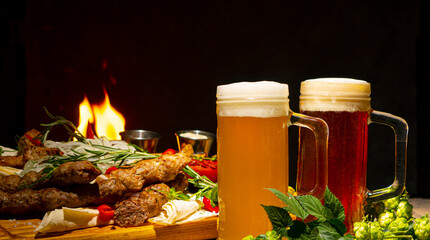 Glass of foamy dark beer and light beer on a background of grilled meat and vegetables