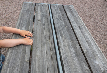 Fototapeta na wymiar Close up view of child's arms on wooden table on playground.