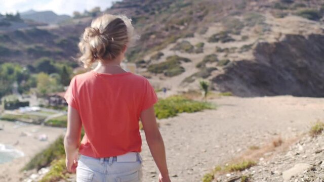 Girl walking in the sun. Camera following her from behind. Summer holiday, walking towards the beach. High quality FullHD footage