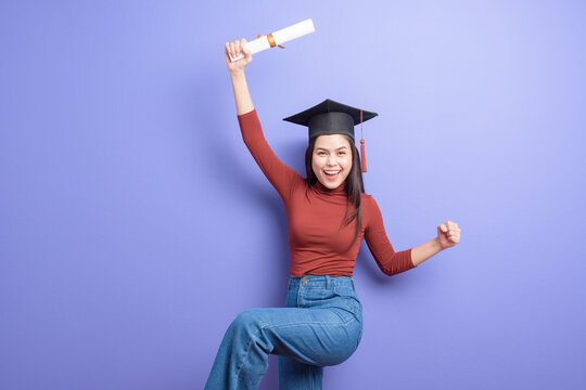 Portrait of young University student woman with graduation cap on violet background