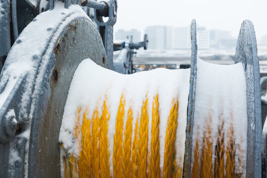 Snow on a mooring winch in ropes, close-up. Snowstorm while the ship is mooring.