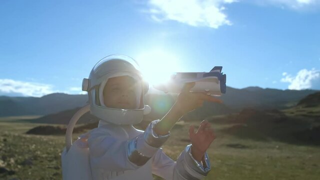 Little young happy child boy wearing astronaut uniform and helmet cosmonaut playing, launching toy shuttle. Space man, Kid big dream flying, childhood, freedom, travel, future, professions concept