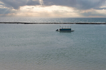 Fototapeta na wymiar Beautiful Sunset at sea with boat in the water, Barra de São Miguel, Alagoas, Brazil.