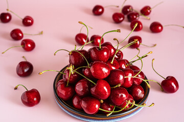 Fototapeta na wymiar Fresh ripe cherry on plate on pink background. Copy space.