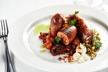 Grilled sausages sauce on a white plate with herbs, on a festive table, light background, copy space